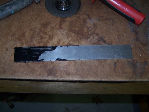 1995 Ford Bronco - A metal strip is shown with a partial black coating, resting on a wooden surface next to a grinder.