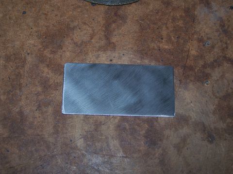 1995 Ford Bronco - A rectangular metal plate with brushed finish rests on a textured wooden surface.