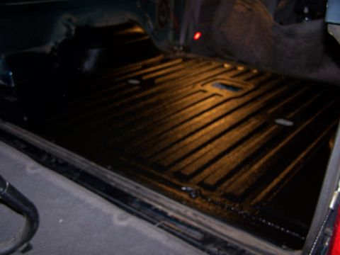1995 Ford Bronco - The ribbed texture of a truck bed liner is visible, with tie-down points integrated into the design.