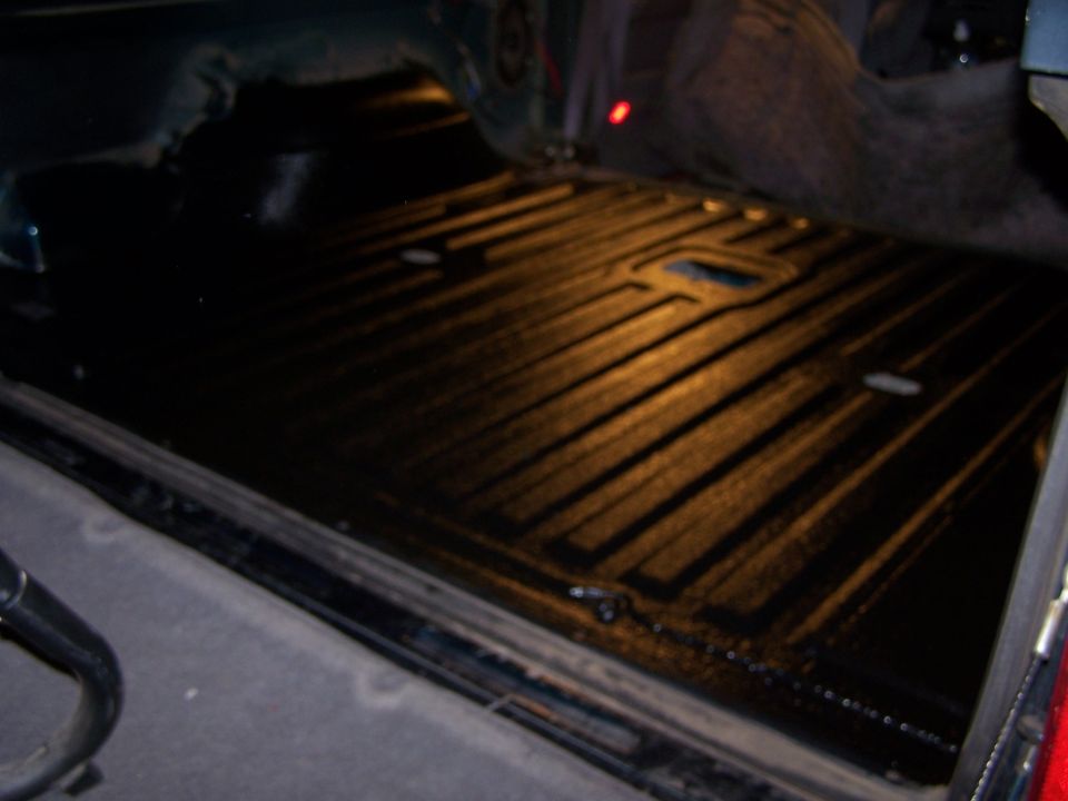 Truck bed liner with ribbed texture and tie-down points, viewed from above