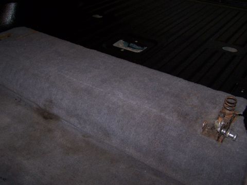 1995 Ford Bronco - Close-up of the carpeted cargo area interior, showing a latch mechanism with a spring.