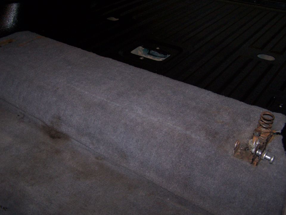 Carpeted interior cargo area with a spring-loaded latch mechanism