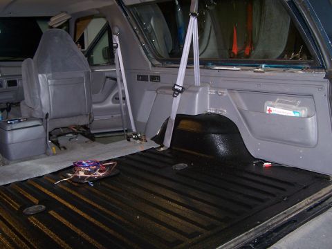1995 Ford Bronco - The rear interior of an SUV shows a freshly coated cargo bed and a first-aid kit mounted on the side panel.