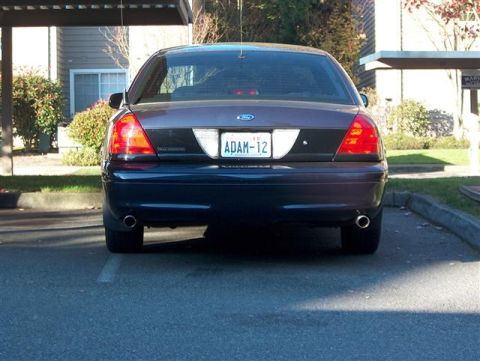 2001 Ford Crown Victoria - The rear of a dark-colored Ford Crown Victoria is parked in a lot, showing its taillights and license plate.