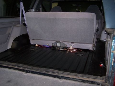 1995 Ford Bronco - The interior cargo area shows a black floor liner and gray rear seats, with visible wiring and a metal component.