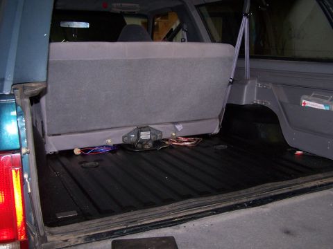 1995 Ford Bronco - The cargo area of a 1995 Ford Bronco features a black bed liner and a folded rear seat, revealing a trailer hitch connection.