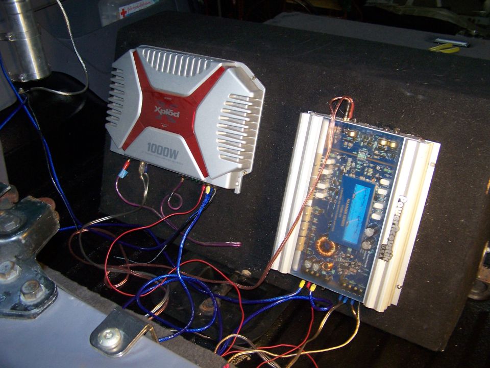 two car audio amplifiers, one is a silver Sony Xplod 1000W, connected with wires