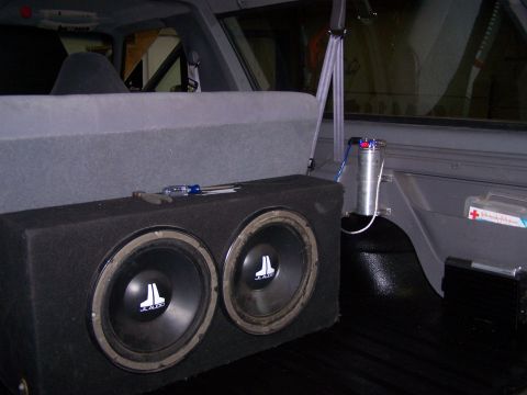 1995 Ford Bronco - The rear interior of a vehicle shows a custom subwoofer box and audio components.