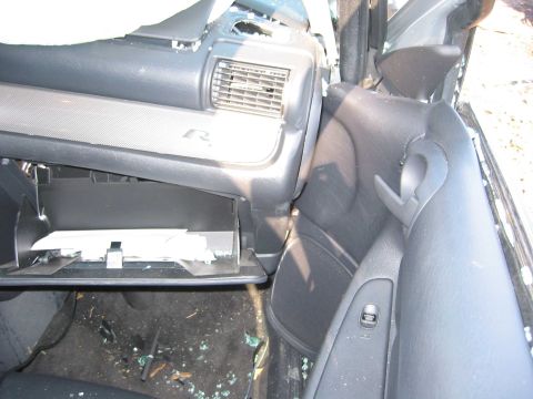 2001 Ford Taurus - Interior view of a damaged 2001 Ford Taurus, highlighting the dashboard and door panel amidst debris.