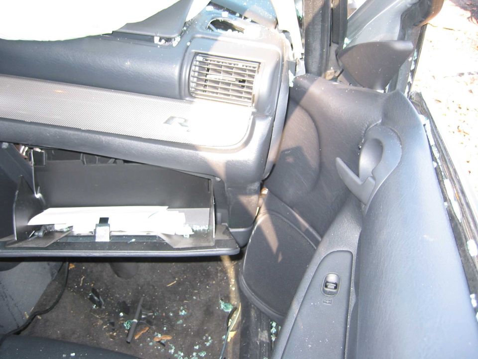 Damaged vehicle interior with open glove box and shattered glass on seat