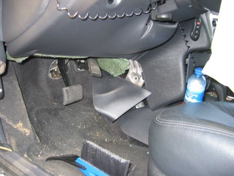 2001 Ford Taurus - The driver's side footwell shows pedals and damaged interior trim, with a water bottle nearby.