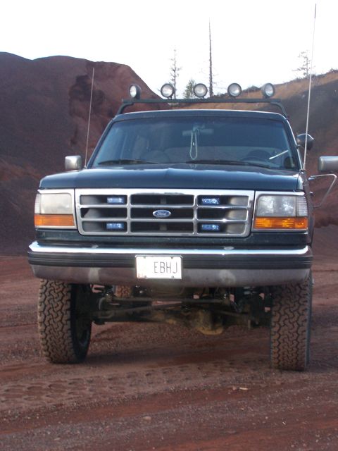 1995 Ford Bronco - This lifted 1995 Ford Bronco is equipped with auxiliary lights on its roof rack and a front license plate reading 'EBHJ'.
