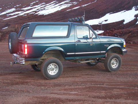1995 Ford Bronco - This lifted 1995 Ford Bronco is parked on a dirt road with a mountainous, snow-dusted background.
