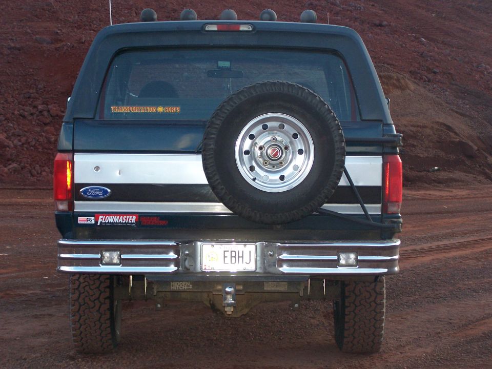 Dark blue Ford Bronco rear with spare tire mounted, chrome bumper, and "EB HJ" license plate