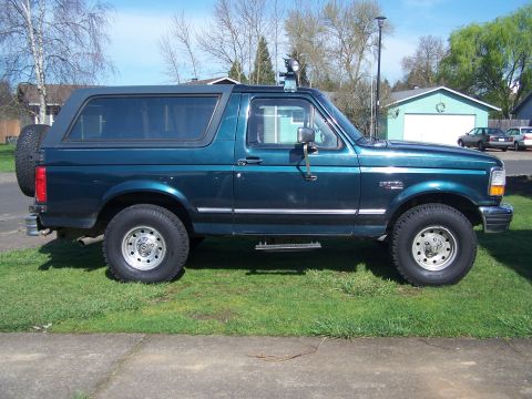1995 Ford Bronco - Side profile of a lifted 1995 Ford Bronco in a residential setting.