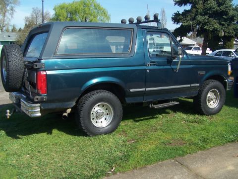 1995 Ford Bronco - This modified Ford Bronco features a lifted suspension and off-road tires, with a spare tire mounted externally on the rear.
