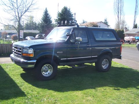 1995 Ford Bronco - This lifted Ford Bronco is parked on a grassy lawn in front of a residential area.