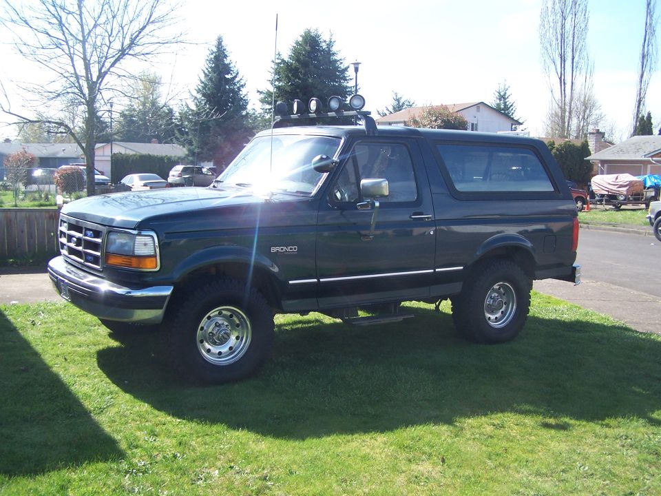 Dark green Ford Bronco parked on a lawn, with roof lights and lifted suspension