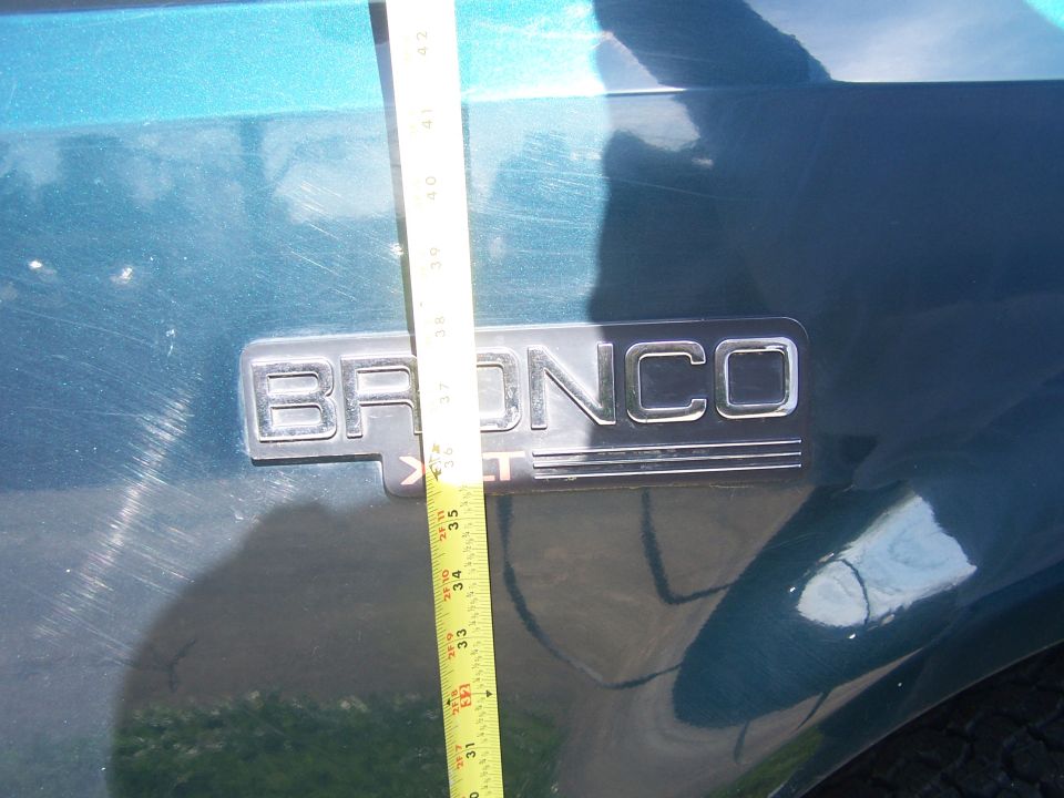 Teal Bronco emblem with tape measure showing height