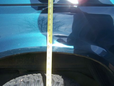 1995 Ford Bronco - A tape measure is used to measure the height of the vehicle's fender above the tire.