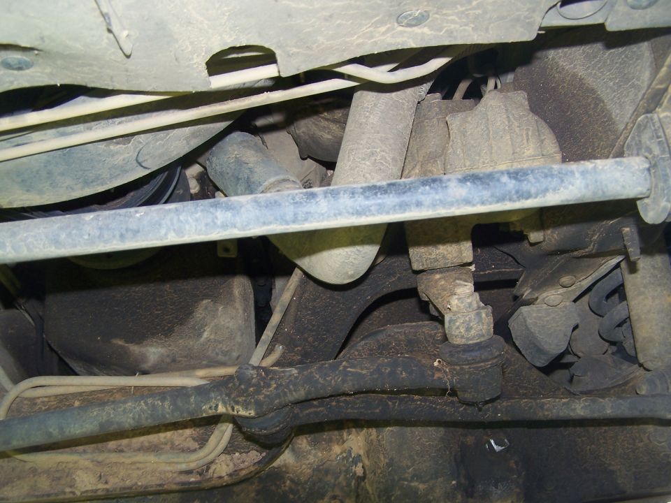 Underside view of a vehicle's suspension and steering components, showing tie rods and ball joints