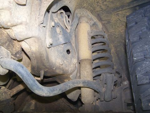 1995 Ford Bronco - Close-up of the vehicle's undercarriage shows suspension parts, including a shock and coil spring.