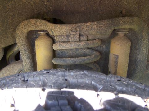 1995 Ford Bronco - Close-up of a vehicle's front suspension system, showing shock absorbers and a coil spring.