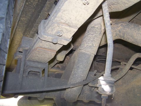 1995 Ford Bronco - Close-up view of the rear suspension components, including leaf springs and a shock absorber, on a lifted truck or SUV.
