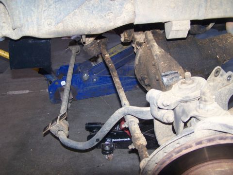 1995 Ford Bronco - The underside of a vehicle is shown with its suspension components and a jack supporting it.