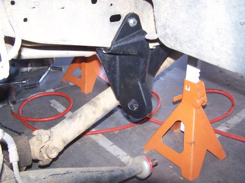 1995 Ford Bronco - A vehicle's undercarriage is shown with a suspension component being worked on, supported by jack stands.