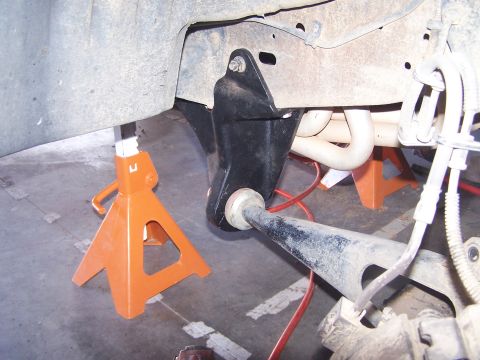 1995 Ford Bronco - Vehicle suspension part is supported by jack stands in a garage.