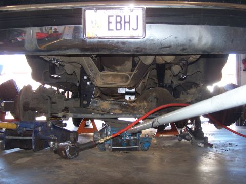 1995 Ford Bronco - Vehicle rear axle and suspension components are supported by jacks and an air hose during work.