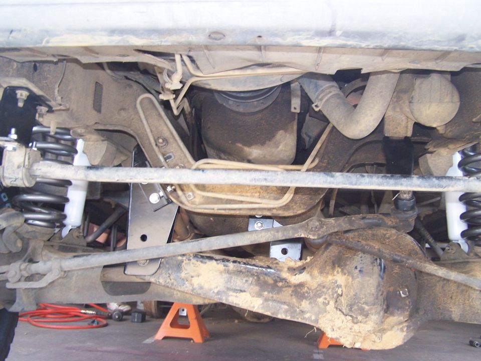 Undercarriage of a vehicle with a lift kit, showing suspension components, differential, and exhaust system