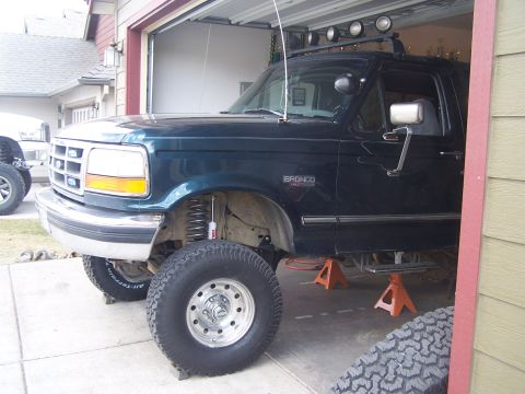 1995 Ford Bronco - This lifted Ford Bronco is undergoing maintenance in a garage, supported by orange jack stands.