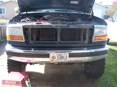 1995 Ford Bronco - Front view of a 1995 Ford Bronco with the hood up and grille removed, revealing the engine compartment.
