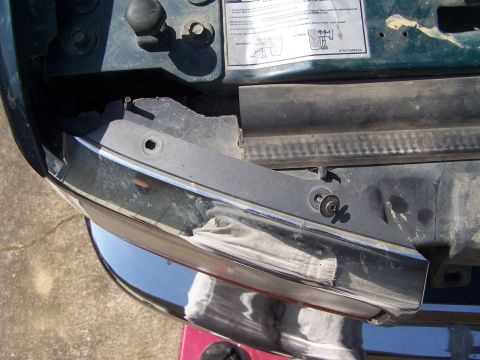 1995 Ford Bronco - A close-up view of the front of a vehicle, focusing on the headlight area and a sticker under the hood.