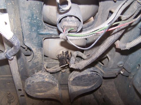 1995 Ford Bronco - Close-up view of vehicle horns and electrical wiring, likely from the front underside of a vehicle.