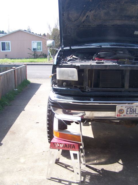 1995 Ford Bronco - Front view of a black Ford truck with its hood up and grille removed, parked in a driveway.