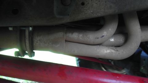 1995 Ford Bronco - Close-up view of vehicle exhaust pipes and a red suspension component.