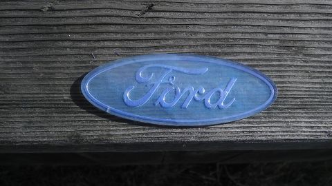 1995 Ford Bronco - Blue Ford oval emblem is shown on a weathered wooden surface.