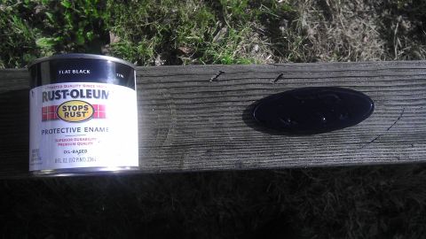 1995 Ford Bronco - A black Ford emblem sits on a wooden surface beside a can of Rust-Oleum protective enamel.