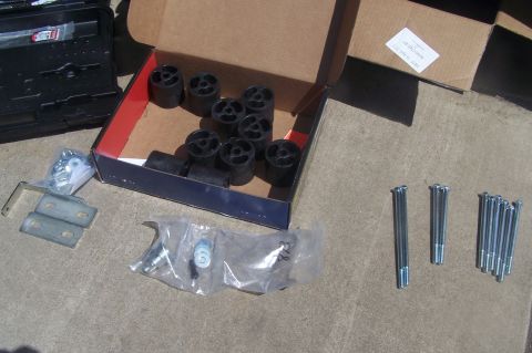 1995 Ford Bronco - A body lift kit with pucks and bolts is laid out on a concrete surface.