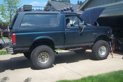 1995 Ford Bronco - This lifted 1995 Ford Bronco is parked in a driveway with its hood up.