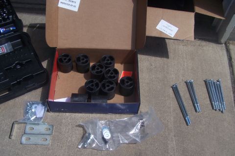 1995 Ford Bronco - A body lift kit is laid out on the ground, including spacers, bolts, and mounting hardware.