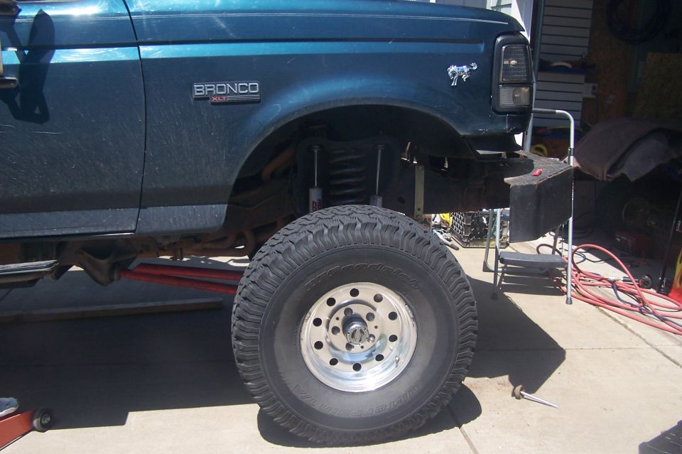 Side view of a dark teal Ford Bronco, showing lifted suspension and large tire. Bronco XLT badge visible