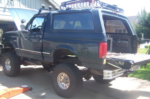1995 Ford Bronco - This lifted Ford Bronco is parked in a driveway with its hood and tailgate open, revealing its interior.