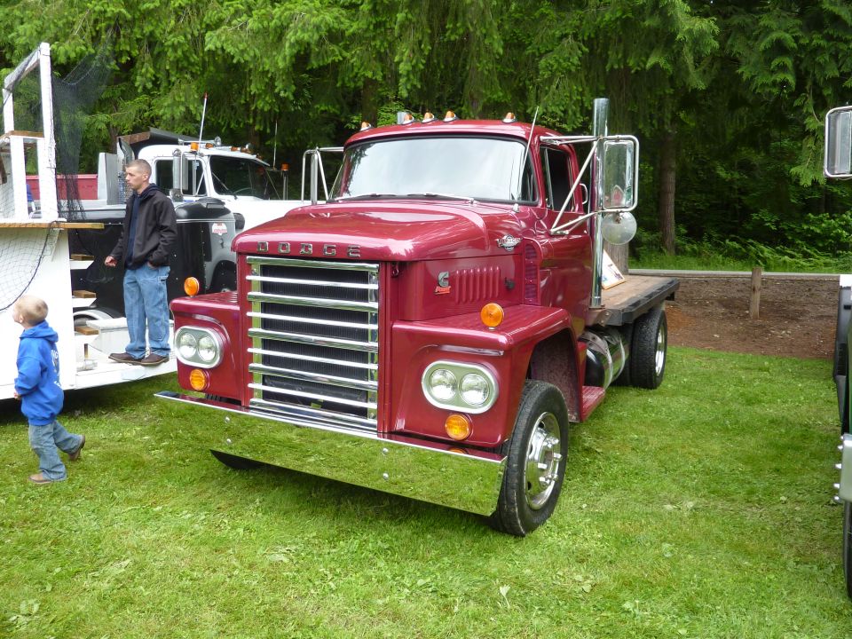 Red Dodge truck with chrome grille and dual headlights, parked on grass