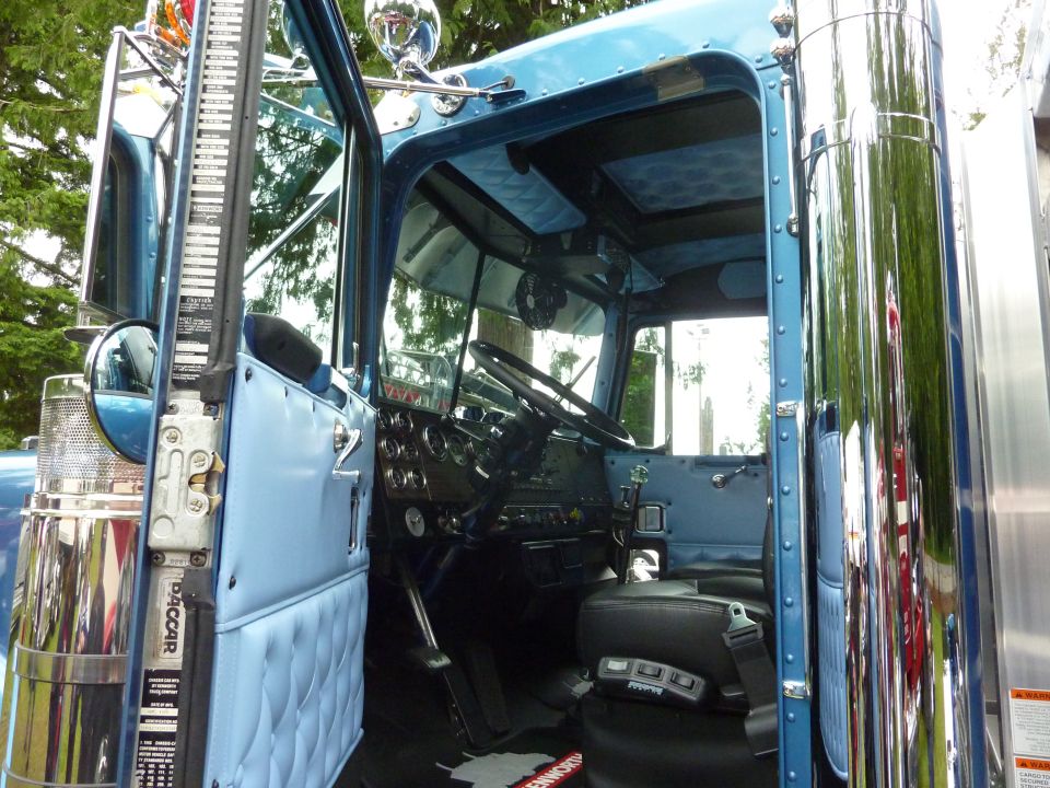 Blue truck interior with black seats and dashboard, door open