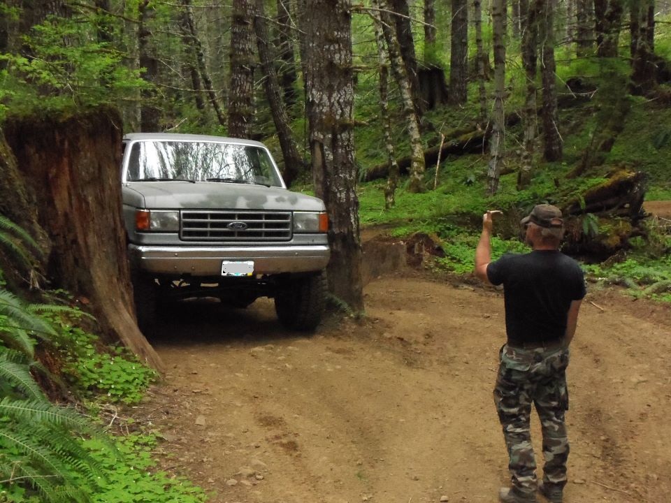 Ford truck on a wooded trail, guy taking photo