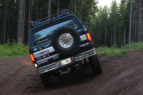 1995 Ford Bronco - 1995 Ford Bronco navigating a dirt trail through a forest.